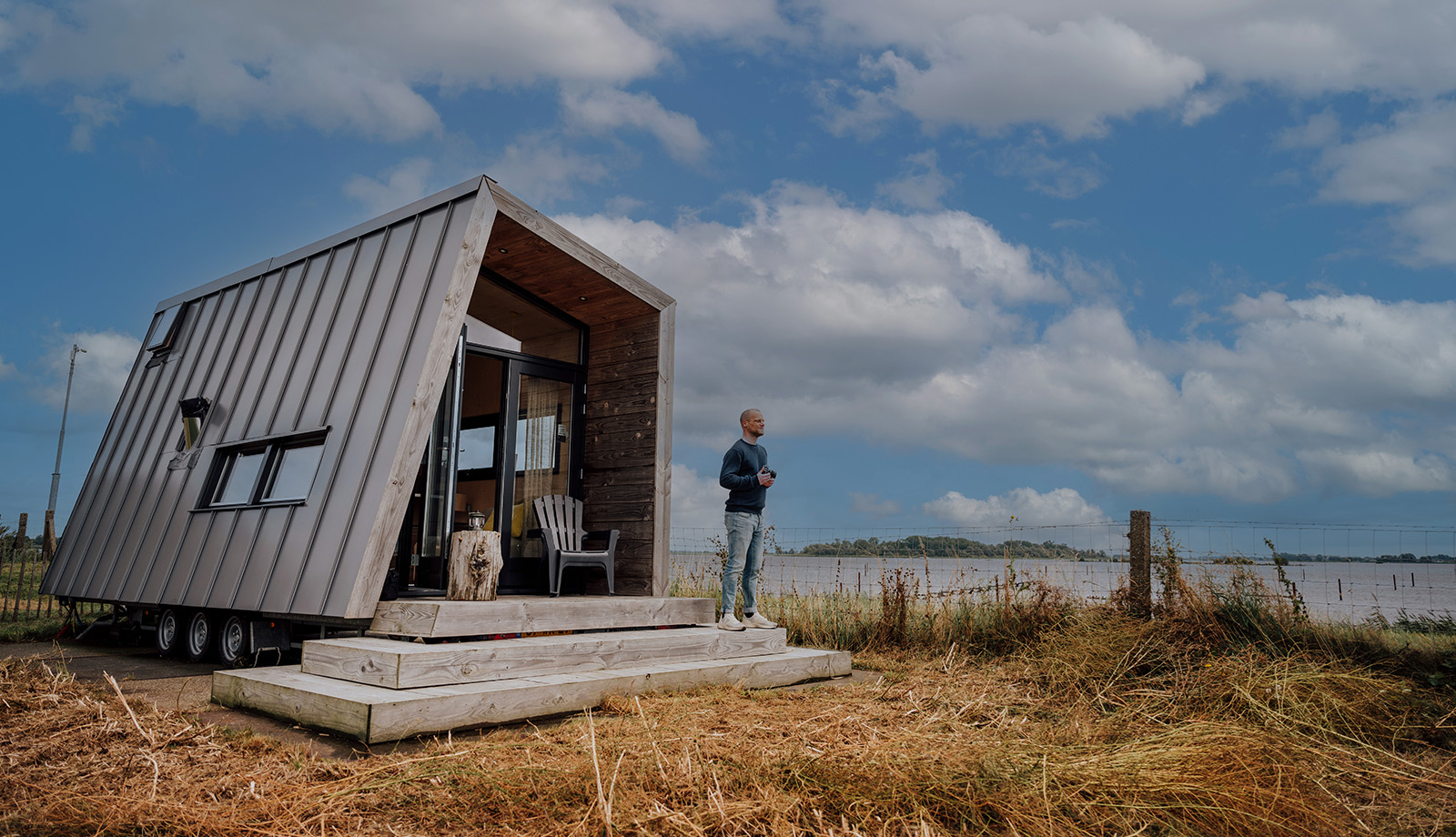Man staat voor het Zuiderkrib Dijkhuisje met dijk en water in Kraggenburg, Flevoland