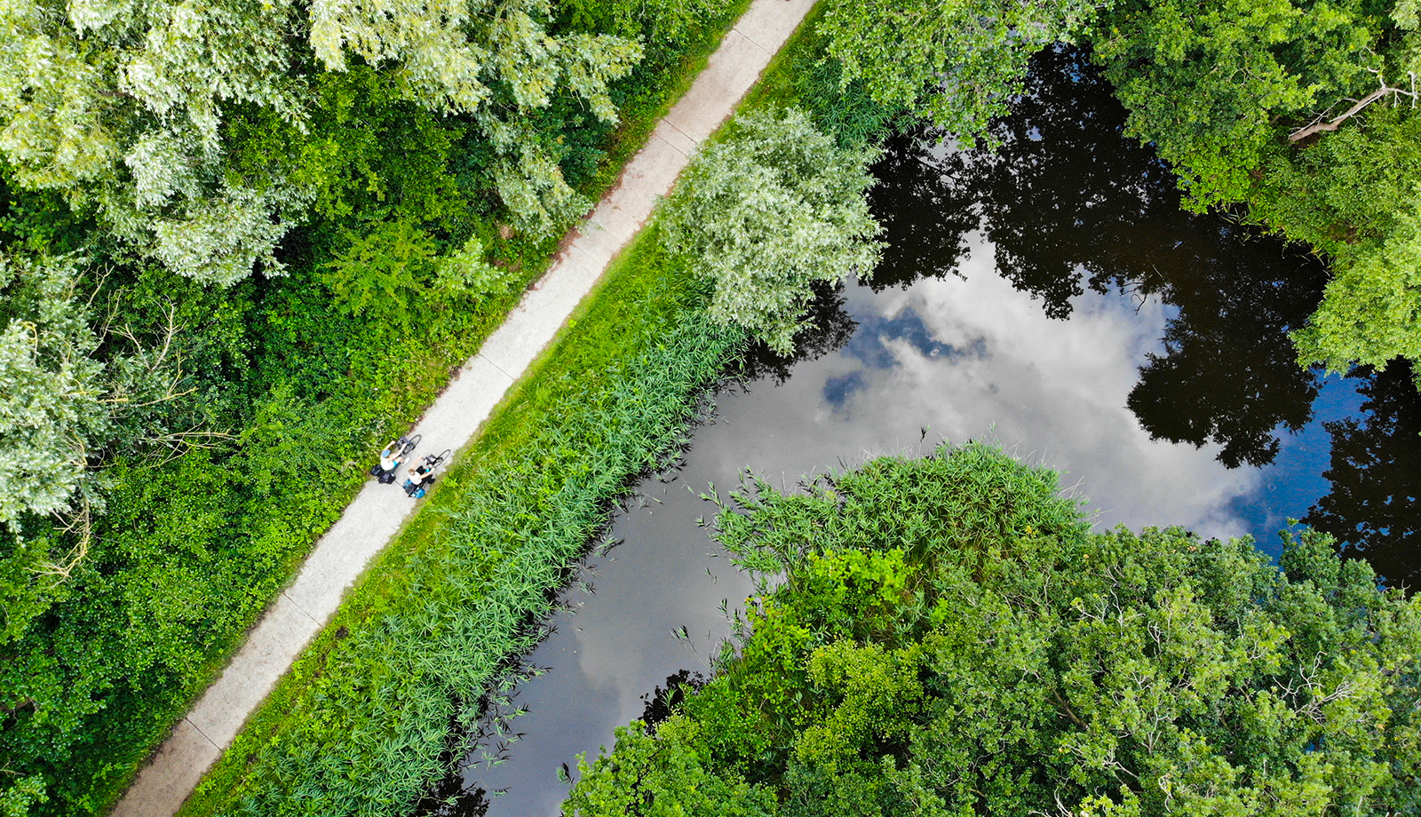 Luchtfoto van fietsers op een pad langs water en natuur in Nederland, passend bij recreatie en de inrichting van de leefomgeving